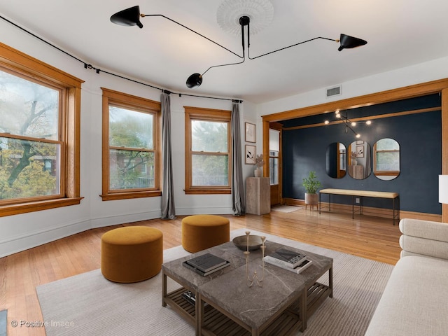 living area featuring baseboards, wood finished floors, and visible vents