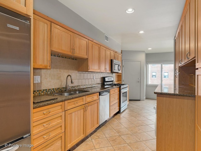 kitchen with visible vents, tasteful backsplash, a sink, dark stone countertops, and stainless steel appliances