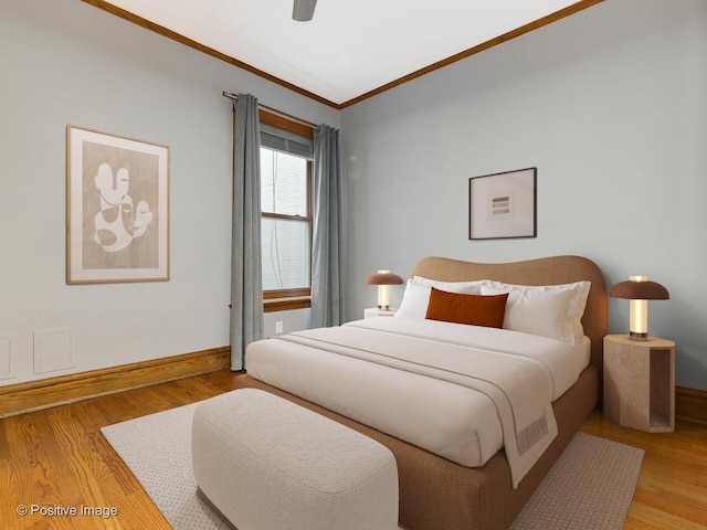 bedroom featuring baseboards, ornamental molding, a ceiling fan, and light wood-style flooring