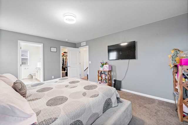 bedroom with visible vents, baseboards, ensuite bathroom, a walk in closet, and carpet flooring