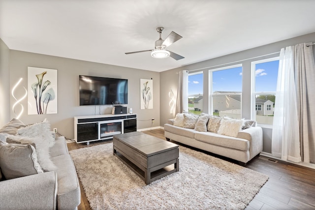 living room with visible vents, a ceiling fan, baseboards, and wood finished floors