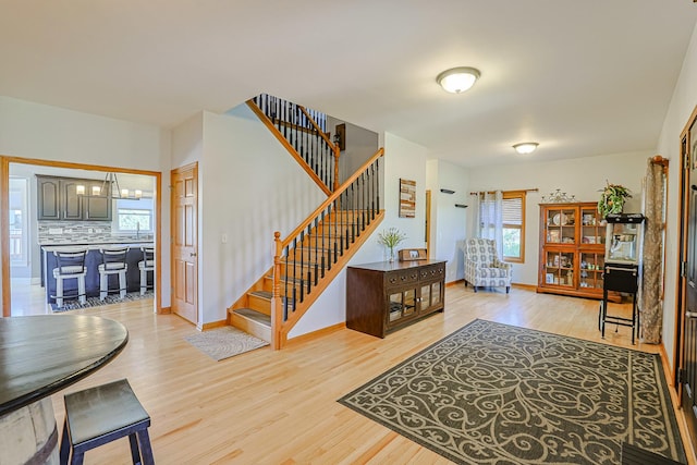 foyer entrance with light wood-style flooring, healthy amount of natural light, and stairway