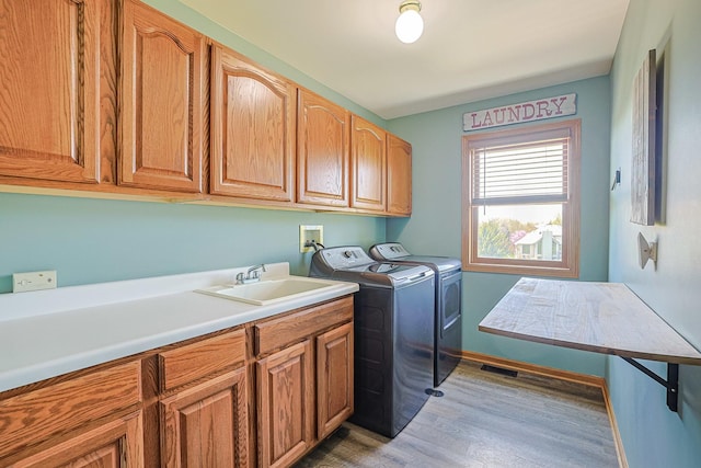 laundry area with cabinet space, washer and dryer, wood finished floors, and baseboards