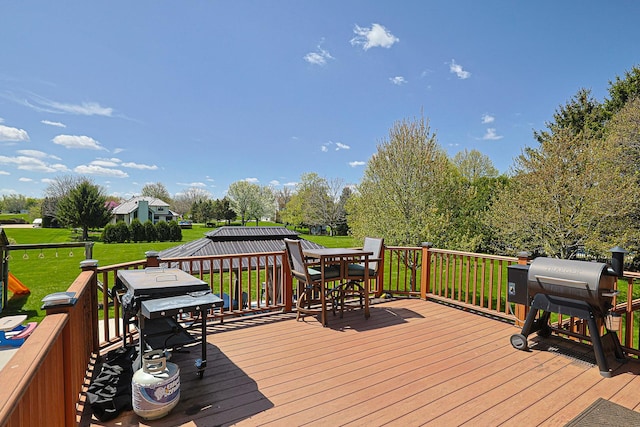wooden terrace with a lawn, outdoor dining area, and grilling area