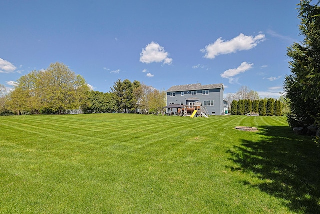 view of green lawn with a wooden deck and stairs