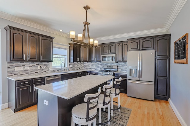 kitchen with stainless steel appliances, a sink, dark brown cabinetry, light stone countertops, and light wood-style floors
