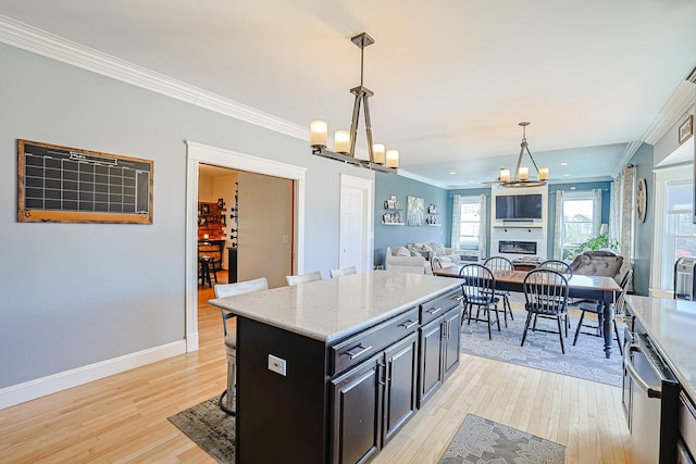 kitchen with light wood-type flooring, dark cabinets, a chandelier, crown molding, and open floor plan