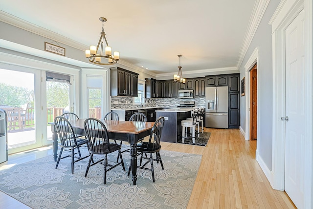 dining space featuring a chandelier, light wood-style floors, crown molding, and baseboards