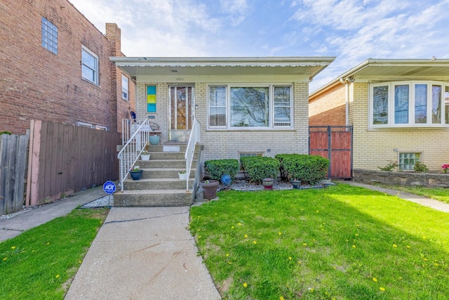 view of front facade featuring brick siding, fence, and a front yard