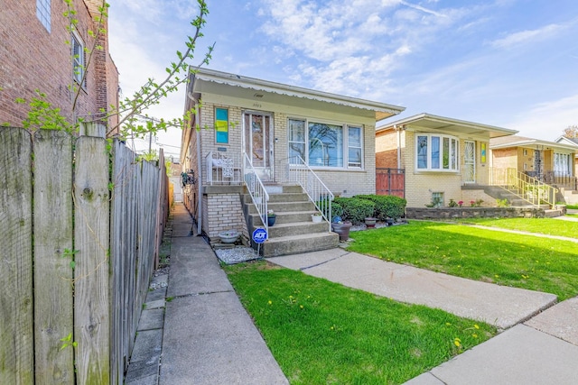 bungalow-style house featuring a porch, stairway, brick siding, fence, and a front lawn