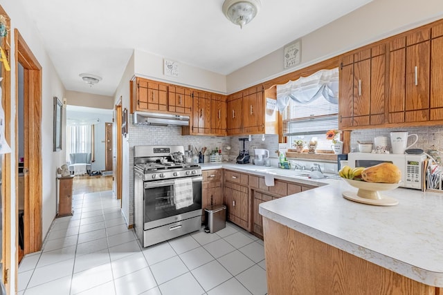kitchen with a healthy amount of sunlight, stainless steel range with gas stovetop, white microwave, and under cabinet range hood