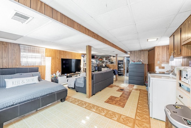 bedroom with wooden walls, visible vents, and a drop ceiling
