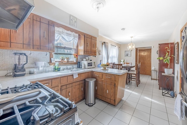 kitchen featuring stainless steel gas range, a peninsula, a sink, and a wealth of natural light