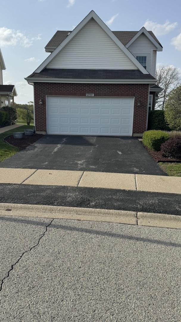 view of front facade featuring brick siding, driveway, and a garage