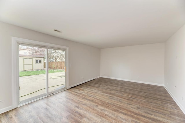 empty room featuring visible vents, baseboards, and wood finished floors