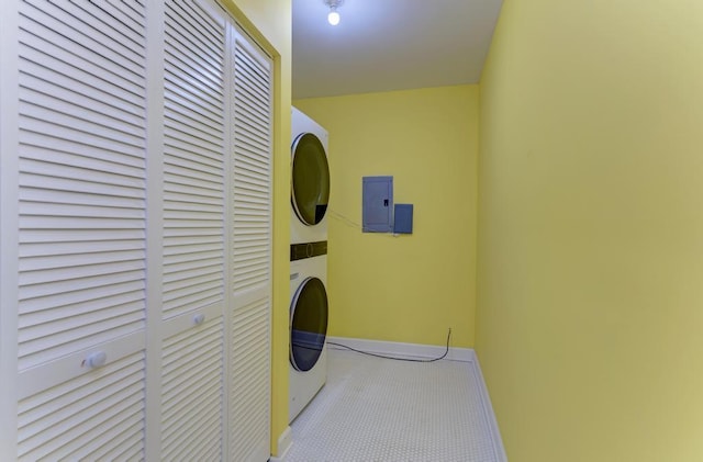 laundry room with laundry area, carpet floors, baseboards, electric panel, and stacked washer / drying machine
