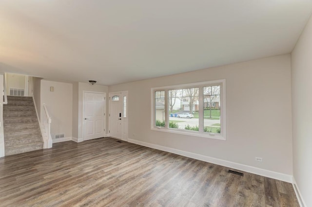 unfurnished living room with stairs, baseboards, visible vents, and wood finished floors
