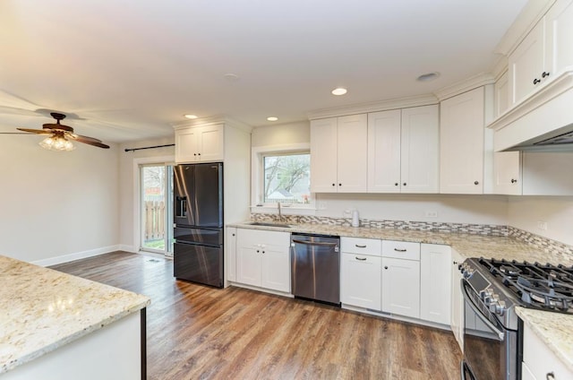 kitchen featuring black fridge, dishwasher, a sink, light wood-style floors, and range with gas stovetop