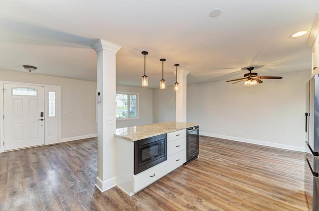 kitchen featuring wood finished floors, black microwave, baseboards, beverage cooler, and hanging light fixtures