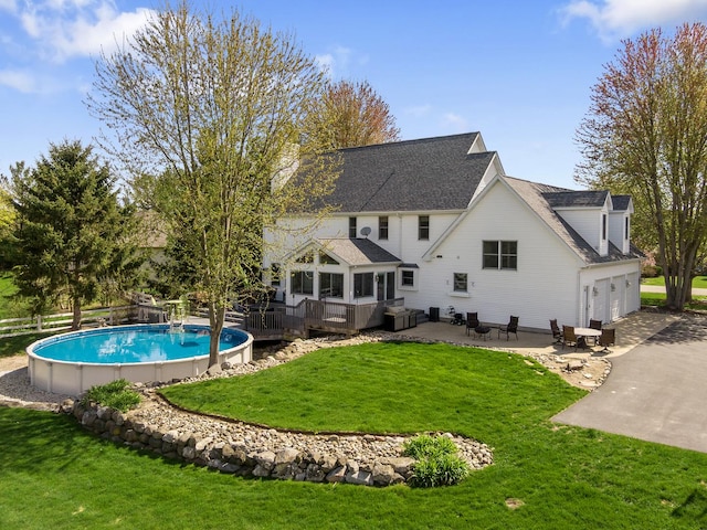 back of property with a garage, a wooden deck, a lawn, and an outdoor pool