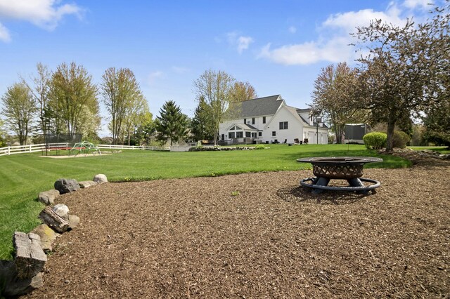 surrounding community with a lawn, an outdoor fire pit, and fence