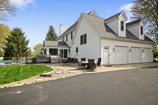 exterior space with roof with shingles, a garage, a chimney, a lawn, and driveway