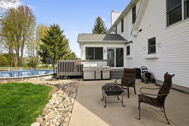 view of patio / terrace featuring an outdoor pool and an outdoor fire pit