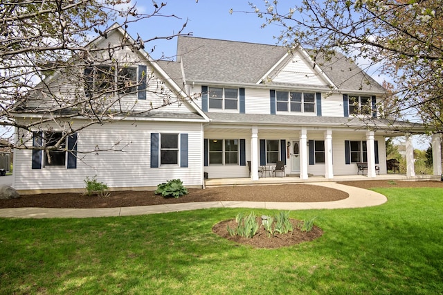 rear view of property with a lawn, a shingled roof, and covered porch