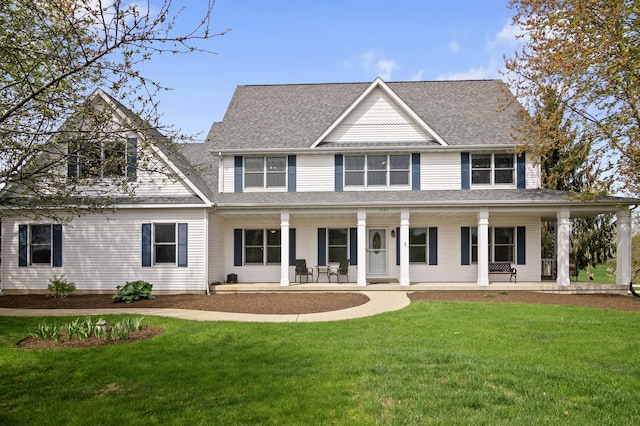 view of front facade with covered porch, roof with shingles, and a front lawn