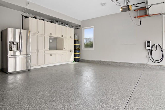 garage with stainless steel fridge and a garage door opener