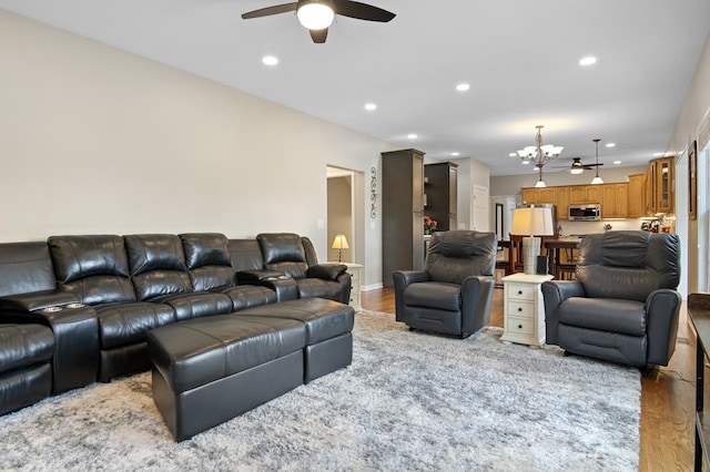 living room featuring recessed lighting, baseboards, ceiling fan with notable chandelier, and light wood-type flooring