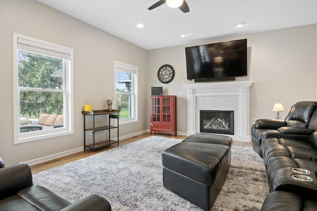 living area with ceiling fan, baseboards, wood finished floors, a tile fireplace, and visible vents