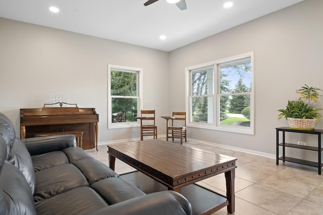 living area featuring a ceiling fan, baseboards, light tile patterned floors, and a healthy amount of sunlight