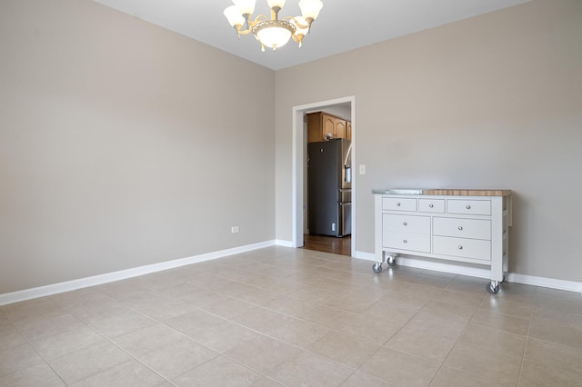 unfurnished room featuring baseboards, a notable chandelier, and light tile patterned floors