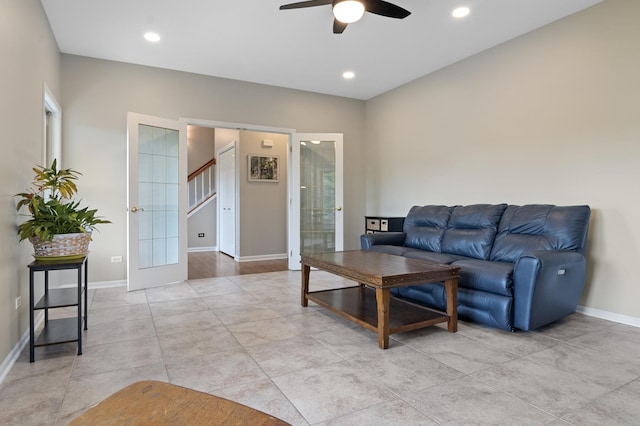 living area featuring baseboards, stairs, ceiling fan, and french doors