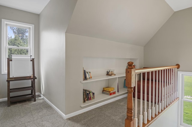 interior space with baseboards, carpet flooring, lofted ceiling, and an upstairs landing