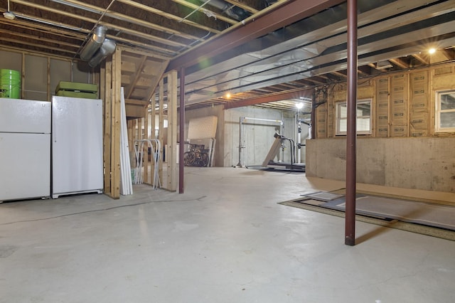 unfinished basement featuring freestanding refrigerator