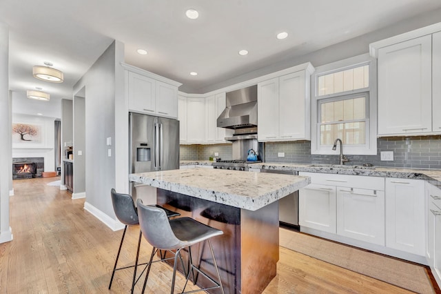 1800 W Melrose St, Chicago, IL 60657 - kitchen featuring wall chimney exhaust hood, a sink, a kitchen bar, baseboards, and a center island