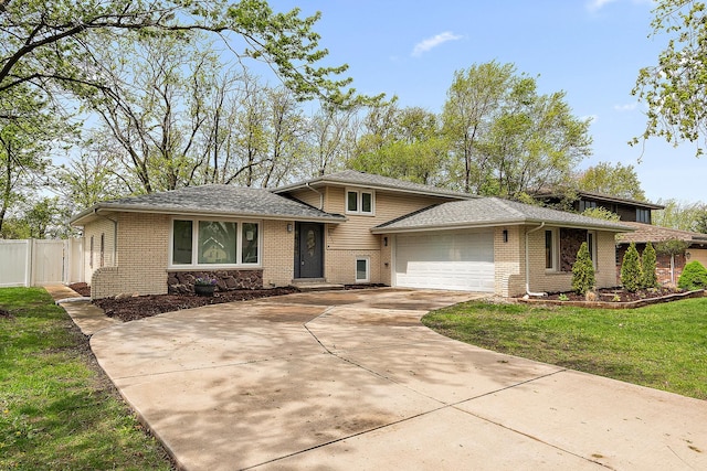 tri-level home with fence, concrete driveway, brick siding, and a garage