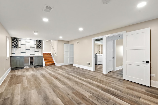 interior space featuring washer / clothes dryer, visible vents, light wood-type flooring, a bar, and stairs