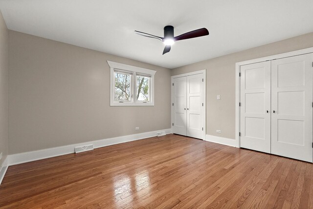 unfurnished bedroom with visible vents, two closets, light wood-style floors, baseboards, and ceiling fan
