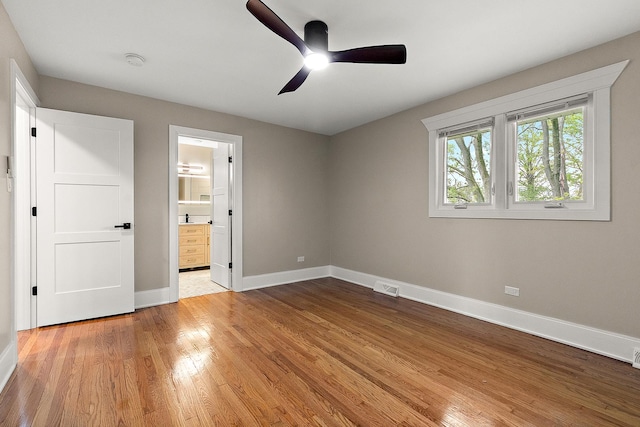 unfurnished bedroom with visible vents, baseboards, ensuite bathroom, a ceiling fan, and light wood finished floors