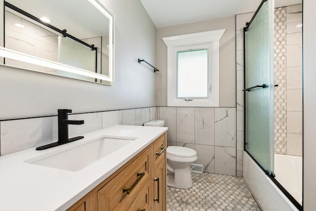 full bath featuring vanity, visible vents, toilet, tile walls, and enclosed tub / shower combo
