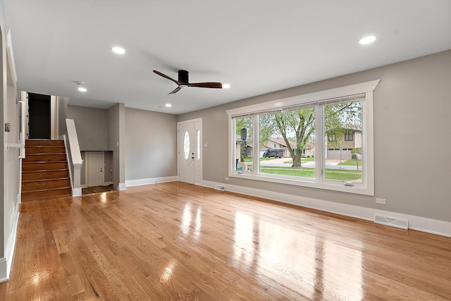 unfurnished living room with a ceiling fan, stairway, baseboards, recessed lighting, and light wood-style flooring