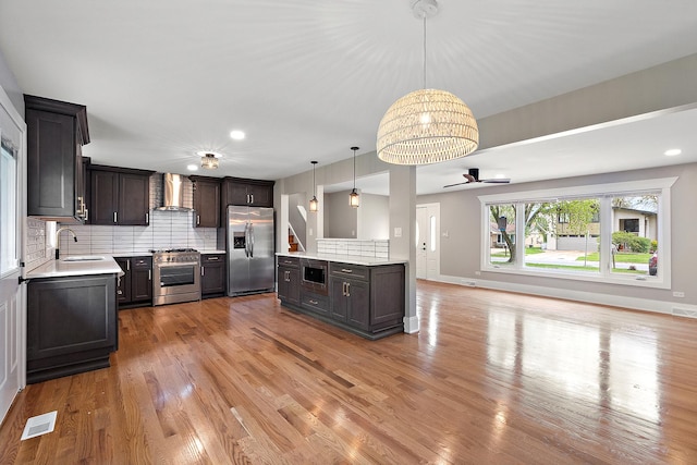 kitchen with wall chimney range hood, light countertops, stainless steel appliances, and visible vents