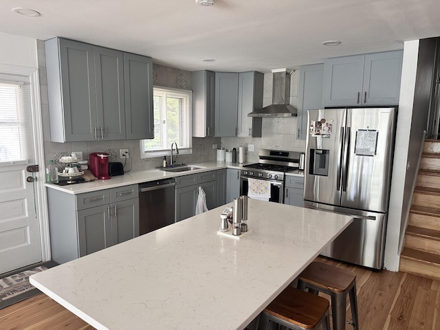 9911 Kedvale Ave, Skokie, IL 60076 - kitchen featuring a sink, a kitchen breakfast bar, wall chimney exhaust hood, stainless steel appliances, and gray cabinetry