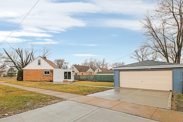 exterior space featuring brick siding, a front lawn, fence, and a detached garage