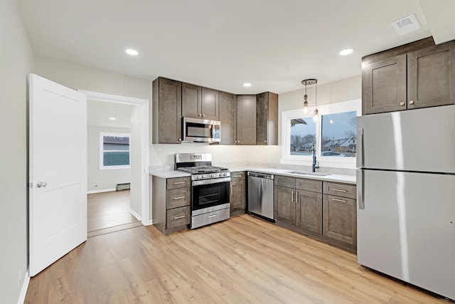 kitchen featuring a sink, light countertops, a baseboard heating unit, stainless steel appliances, and light wood-style flooring
