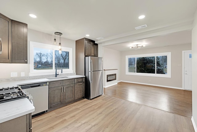 kitchen with visible vents, dishwasher, a sink, freestanding refrigerator, and light wood finished floors