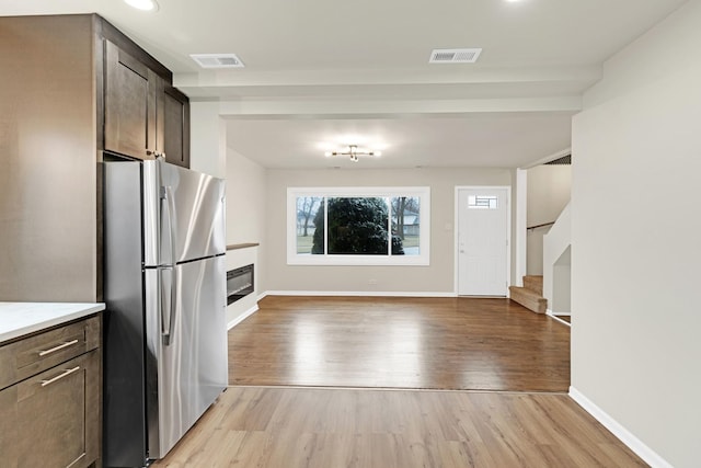 kitchen featuring light wood-style floors, freestanding refrigerator, and visible vents